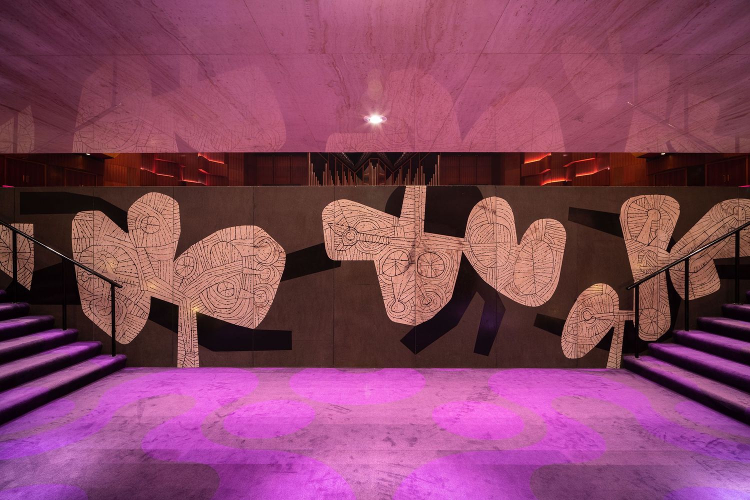 Pink and purple illuminated underground space with heart-shaped graffiti art on concrete wall and staircase.