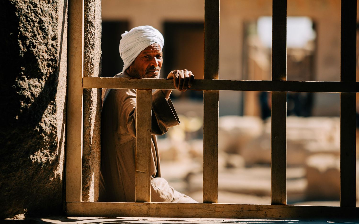 View through rustic wooden window frames showing desert landscape and architecture.