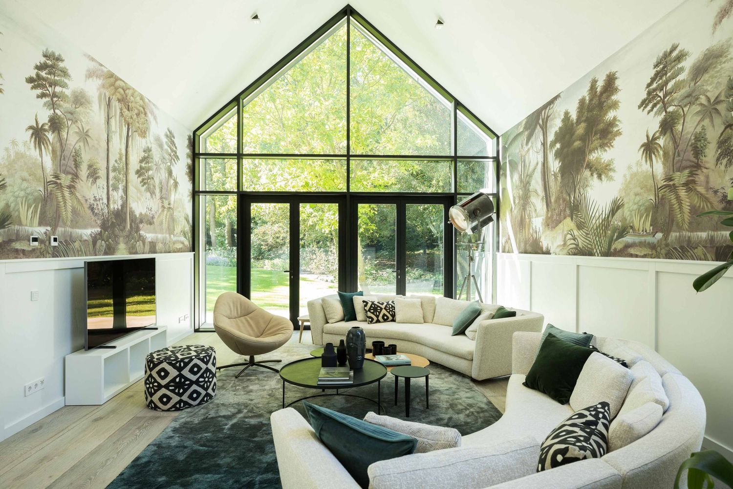 Modern living room with floor-to-ceiling windows showcases white sofas and stunning mountain views in natural light.