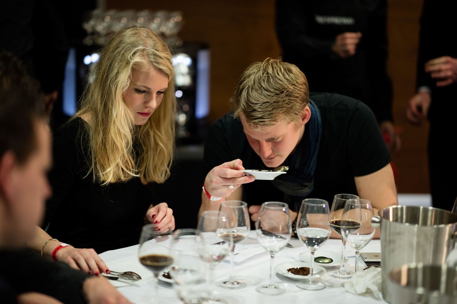 Wine tasting participants evaluating wine samples at a formal event.