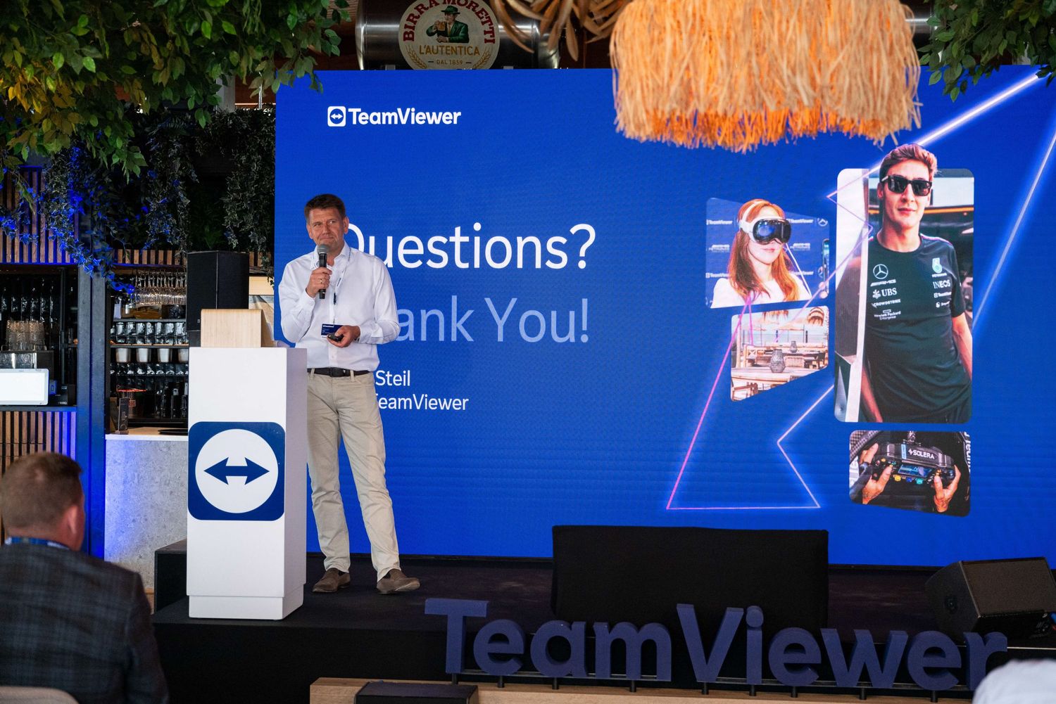 TeamViewer corporate event stage with presentation screens and tropical decor.