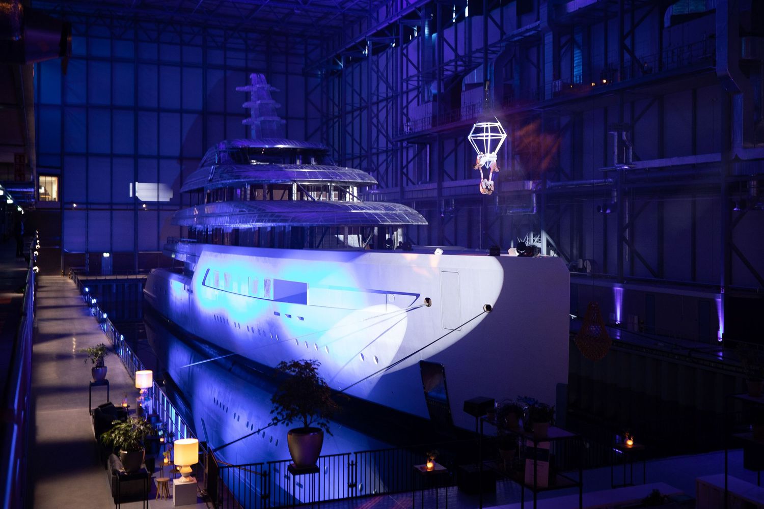 Luxury yachts and boats illuminated by blue lights at night in a marina dock.