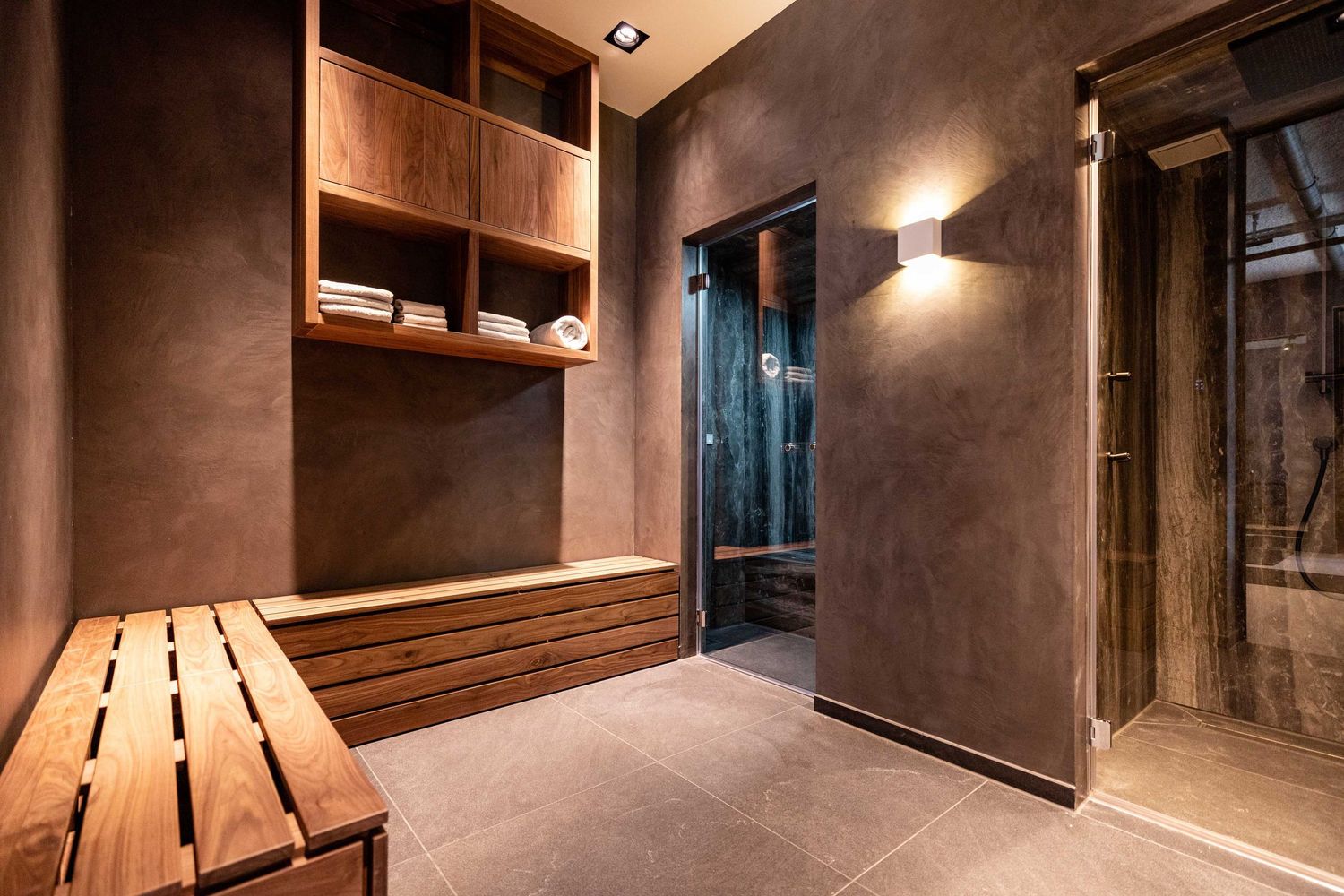 Modern hallway with brown textured walls, recessed lighting, and wooden slat ceiling details creates a warm ambiance.