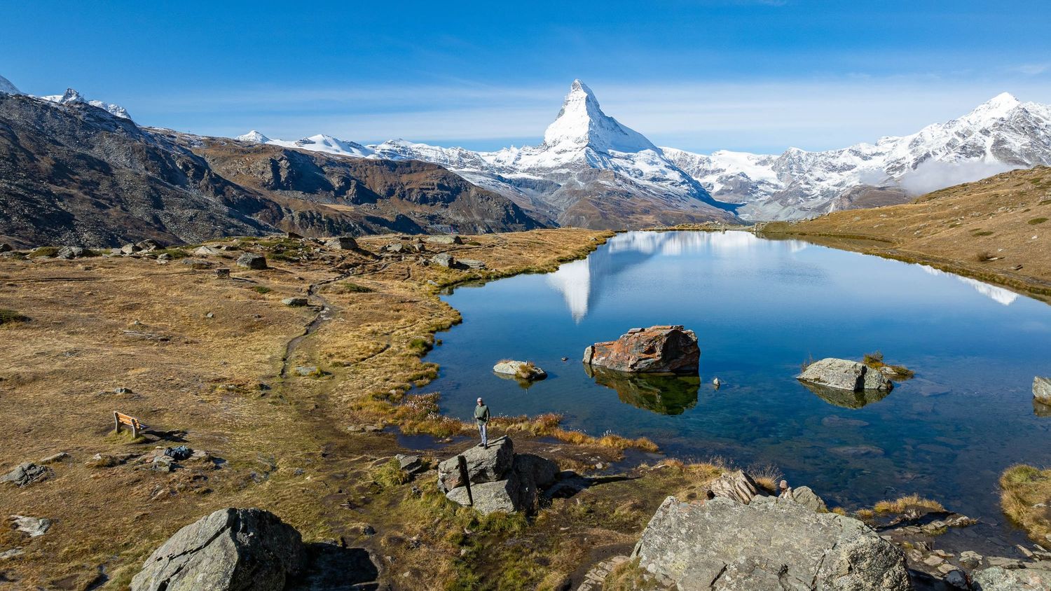 Panoramic mountain landscape with snow-capped peaks and alpine lakes reflecting the majestic Matterhorn.