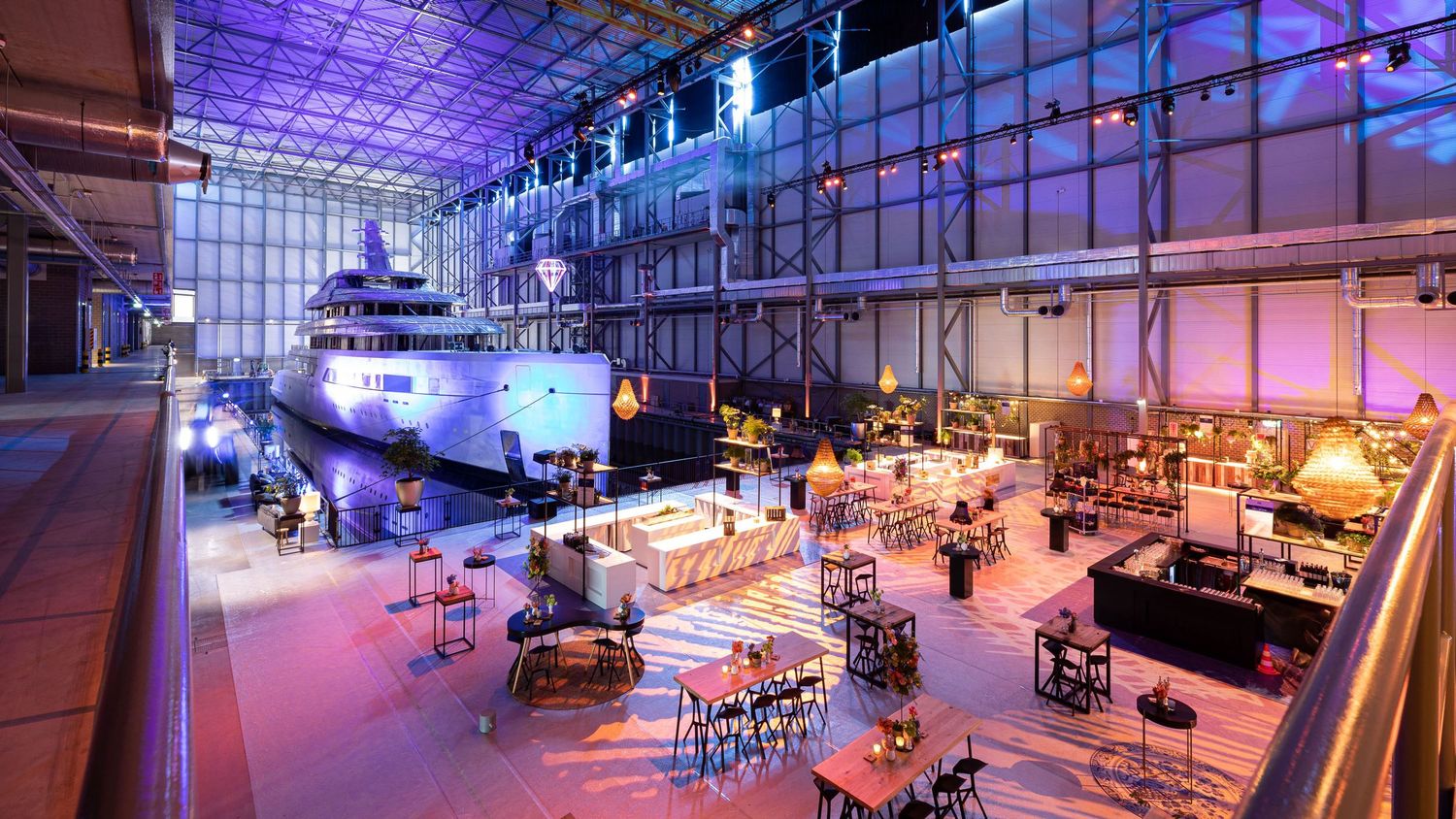 Modern nightclub interior with purple and blue lighting features multiple seating areas and a spacious dance floor.