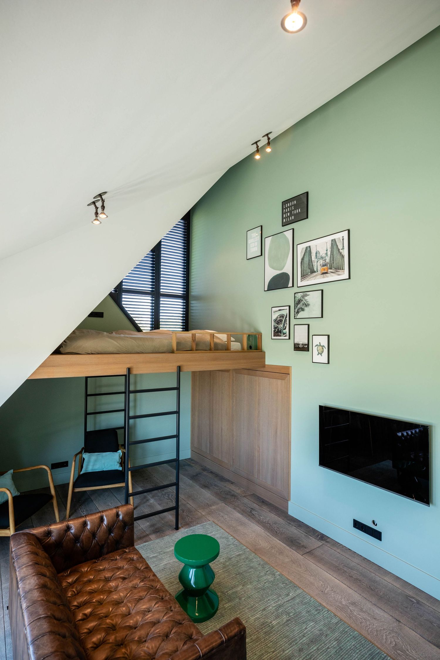 Modern interior room with sloped ceiling, green walls, and minimalist furniture arrangement.