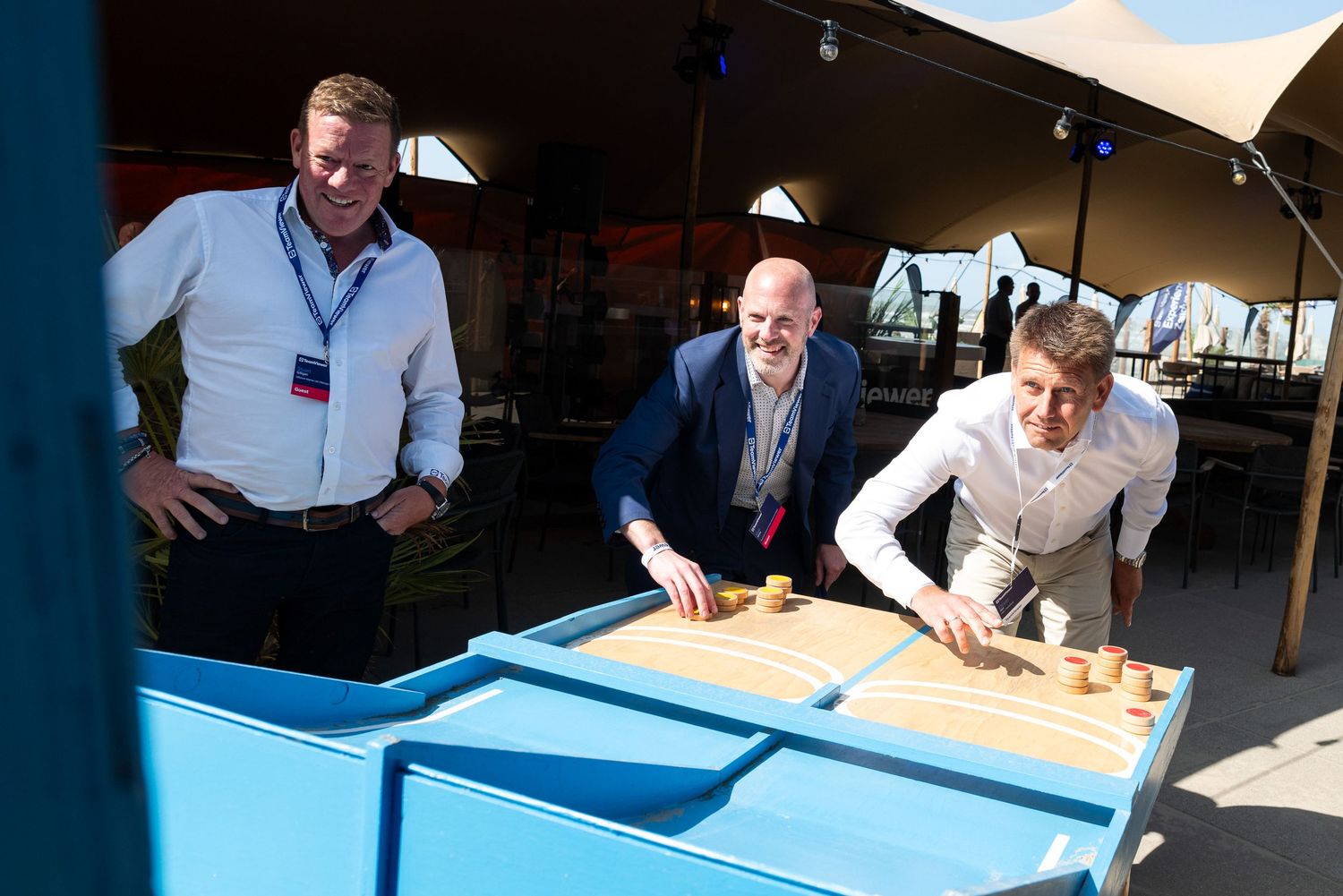 Business professionals signing documents at a bright outdoor meeting space.