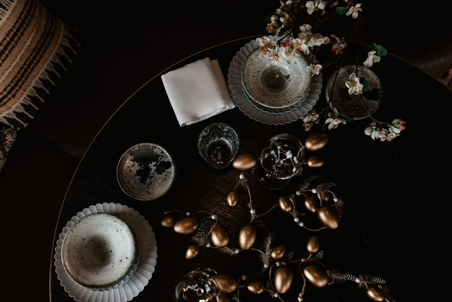Dark and moody food photography of roasted coffee beans scattered on a rustic wooden surface with vintage glassware.