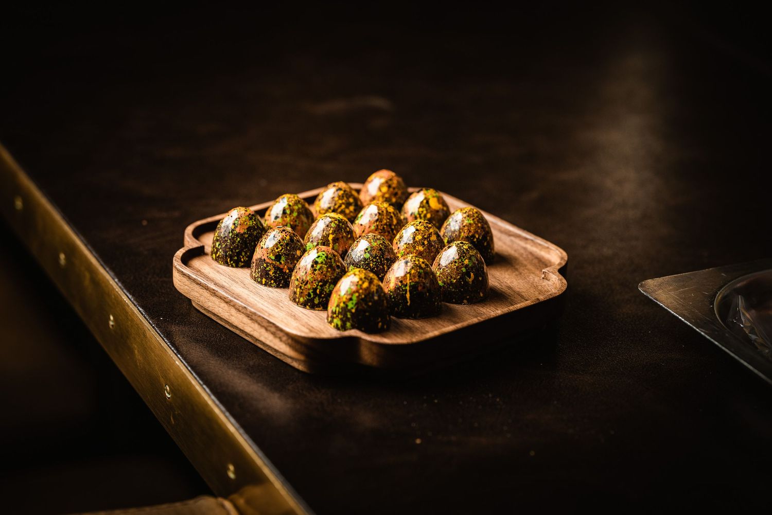 Golden brown takoyaki balls arranged on a wooden serving board in moody lighting against a dark background.