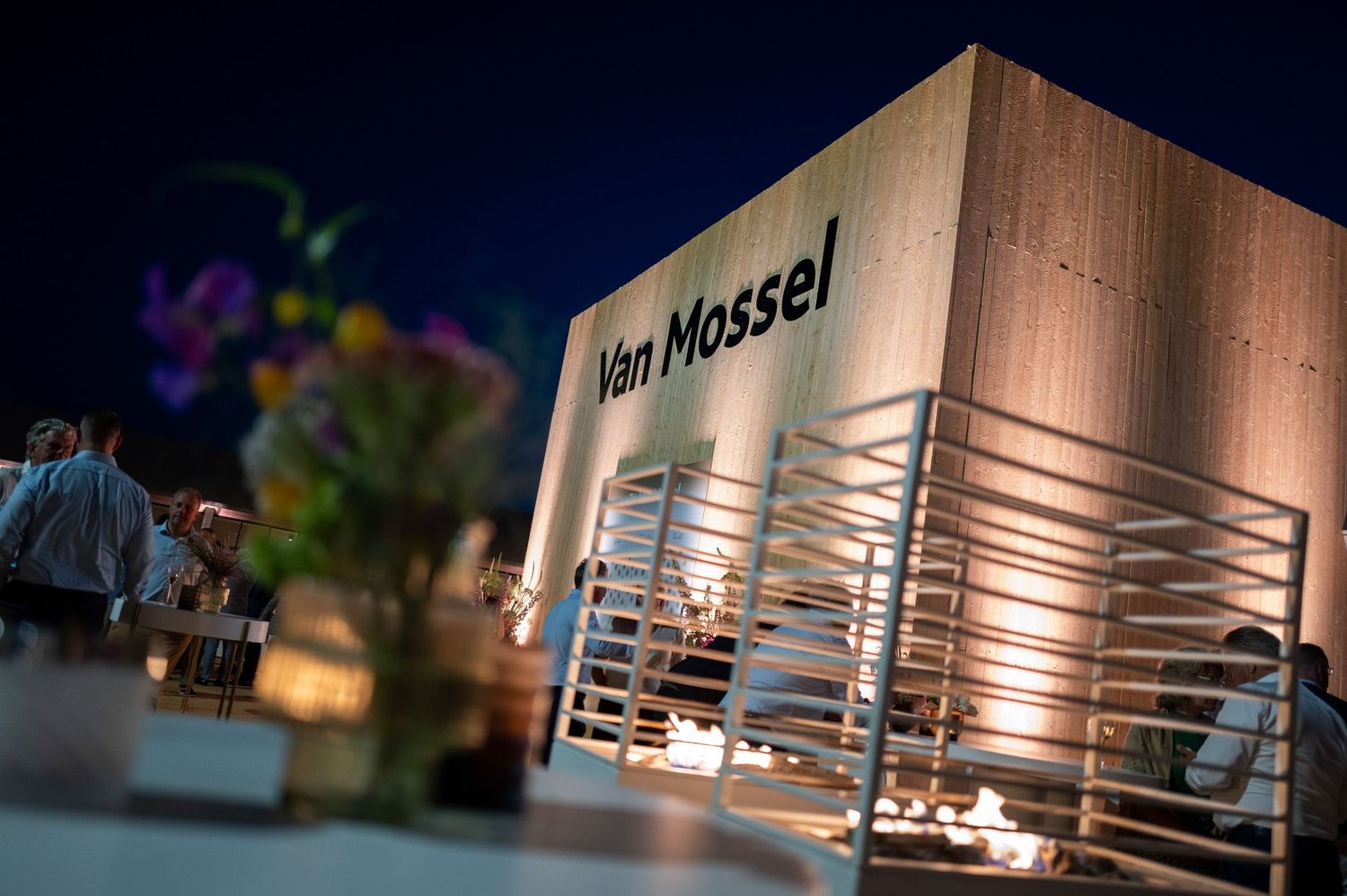 Illuminated modern building exterior with Van Mossel signage at night showing multiple architectural angles.