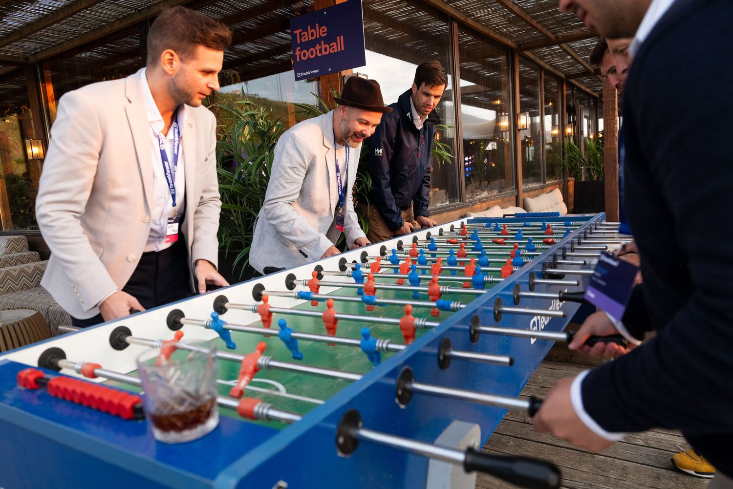 People playing foosball at a corporate event with TeamViewer branding visible.