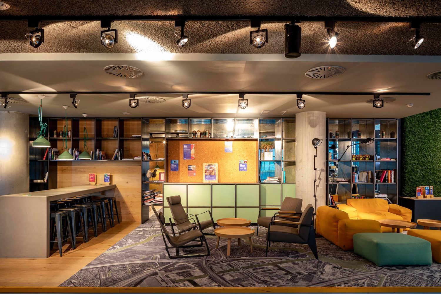 Modern office space with track lighting and colorful wall art features open layout design and comfortable seating areas.