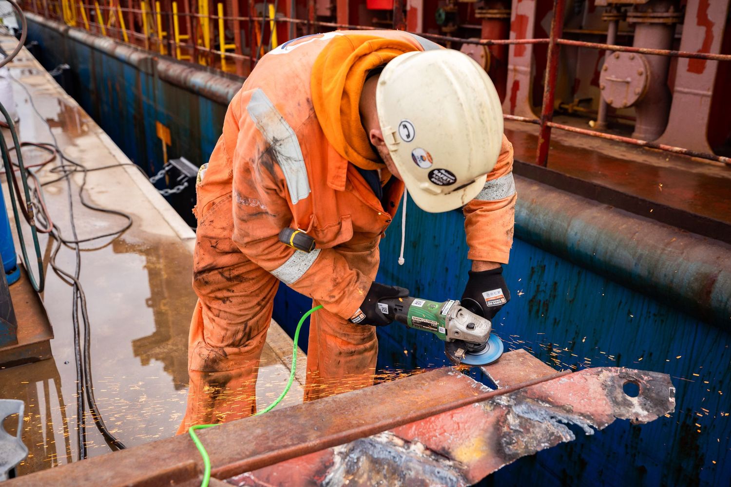 Construction workers in safety gear performing maintenance on industrial equipment.