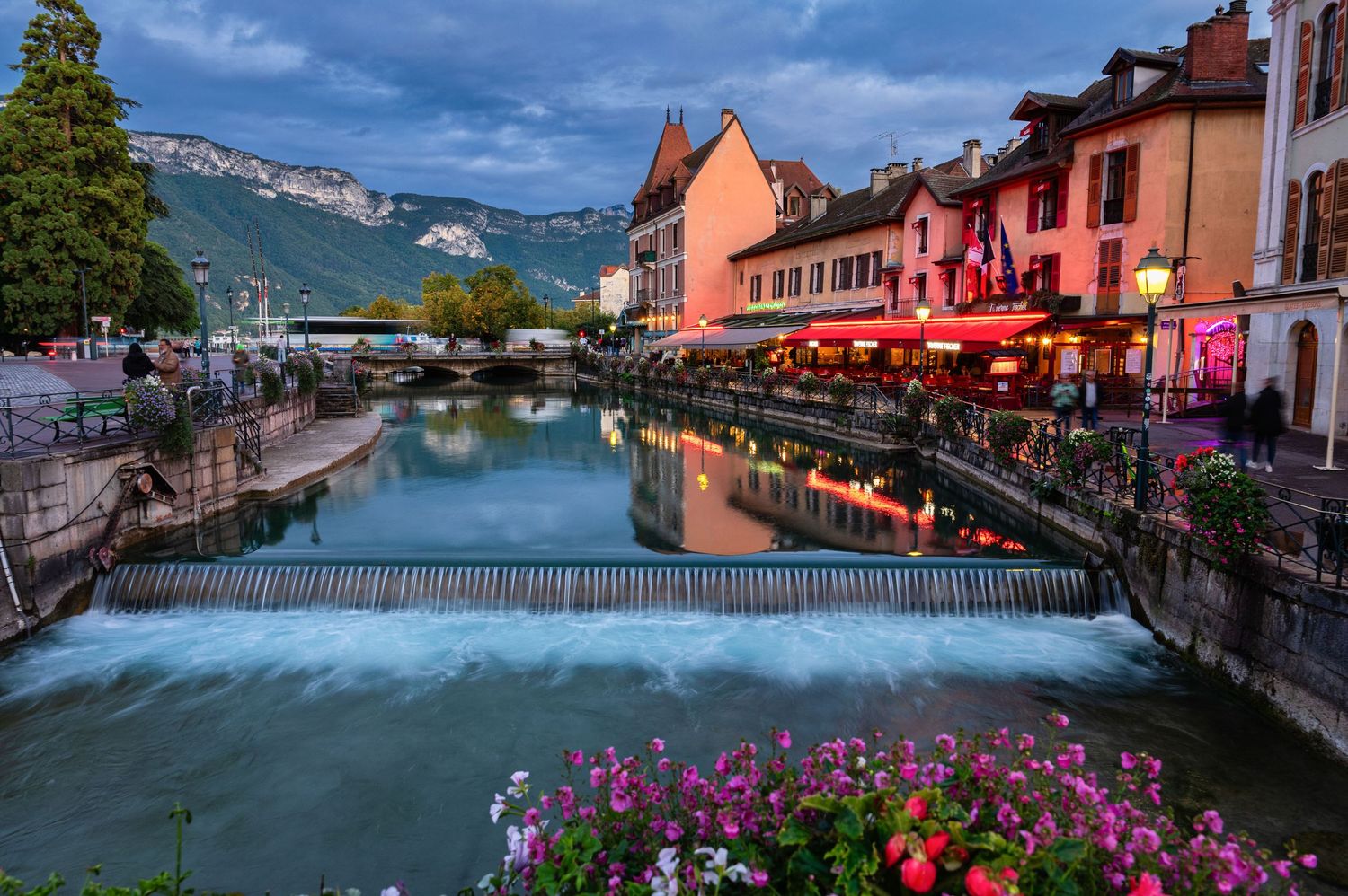 Twilight view of Annecy's old town with illuminated buildings reflecting in the canal waters.