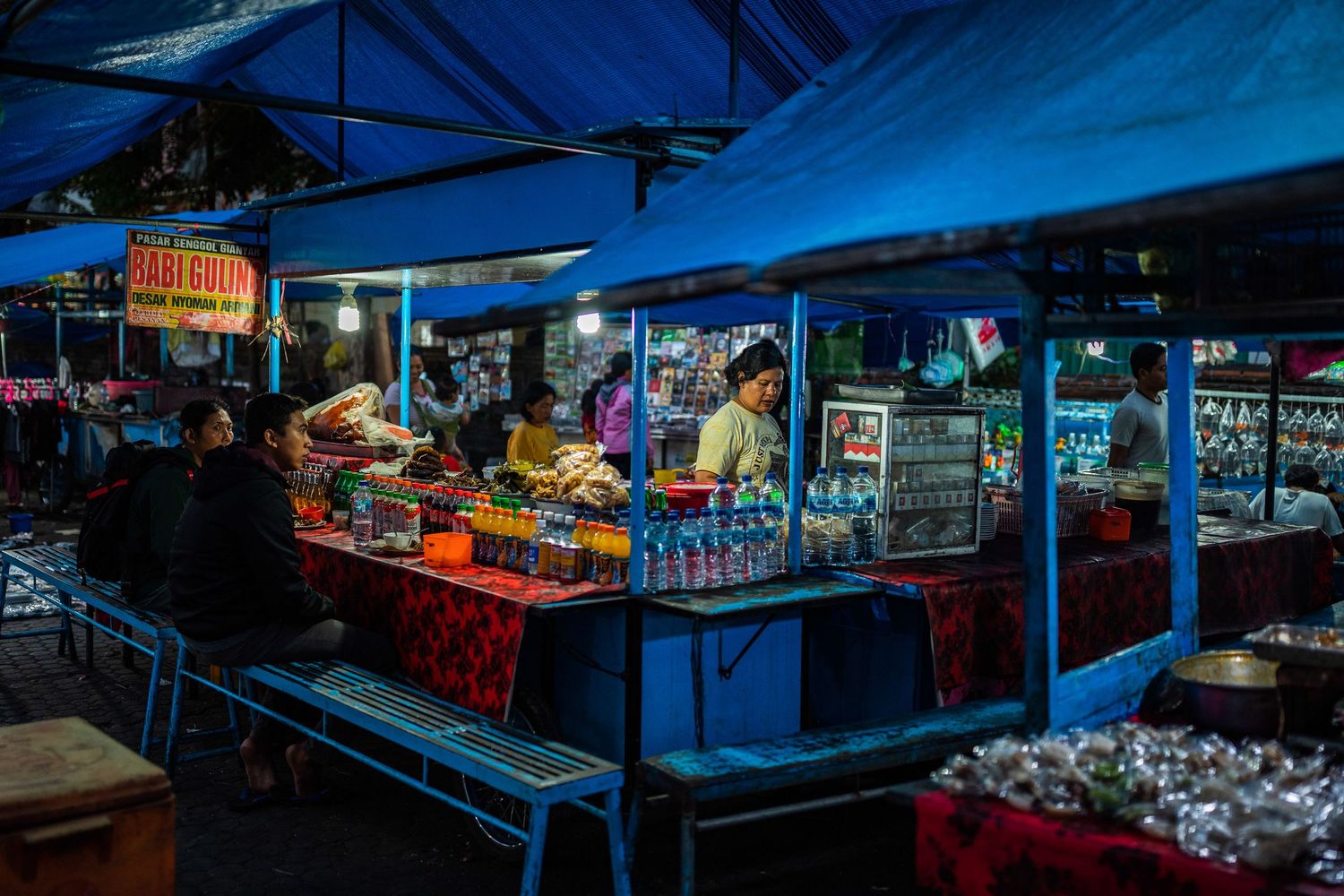 Night market stalls with blue tents illuminated in the darkness.