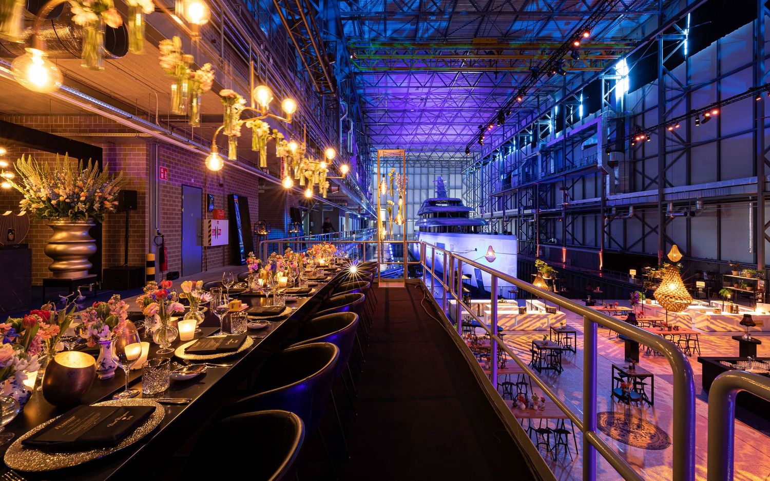 Modern nightclub interior with blue lighting, curved bar counters, and elegant chandeliers illuminating the luxurious space.