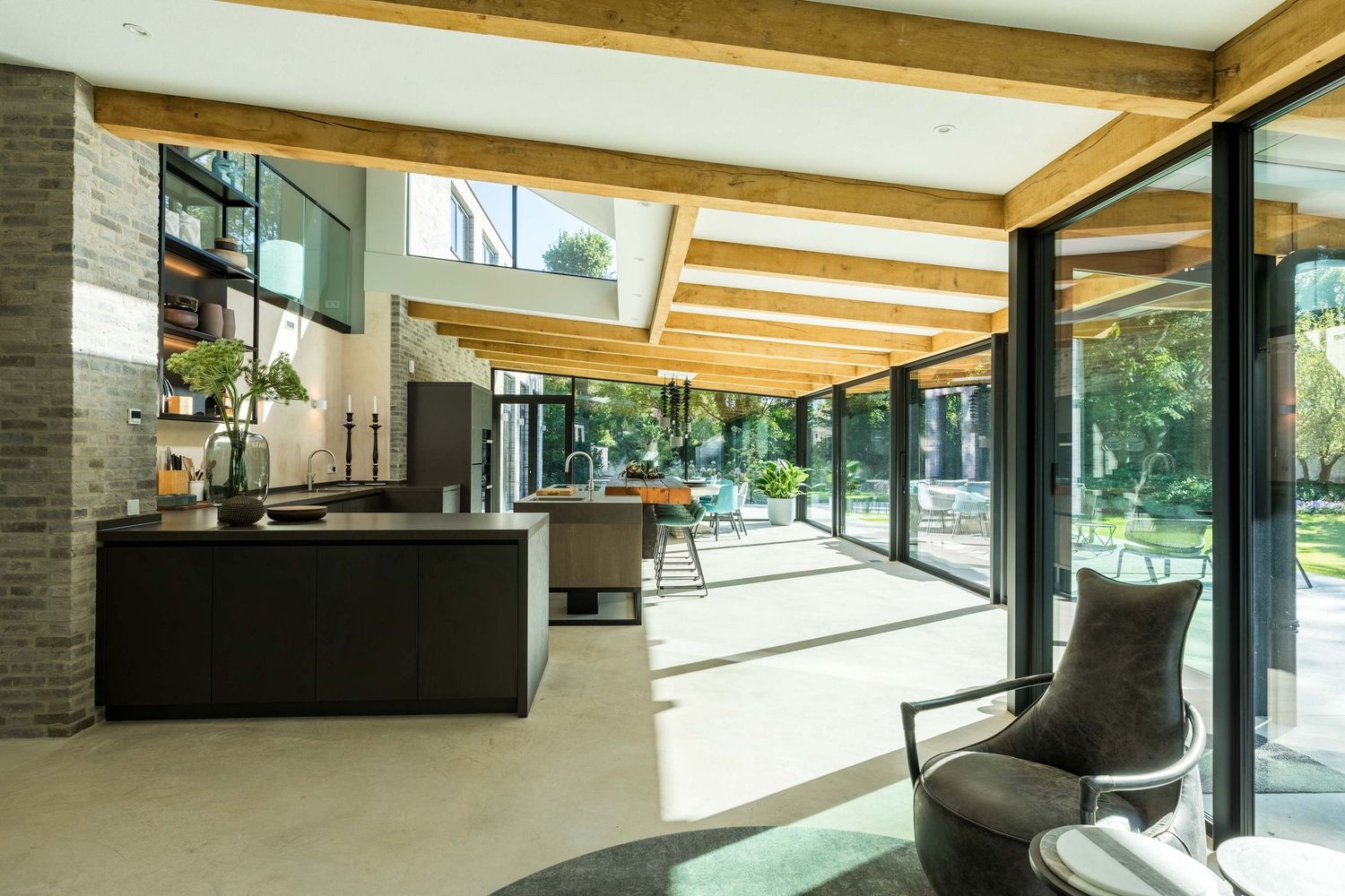 Modern interior of a luxury home with floor-to-ceiling windows, wood beams, and sleek black furnishings.