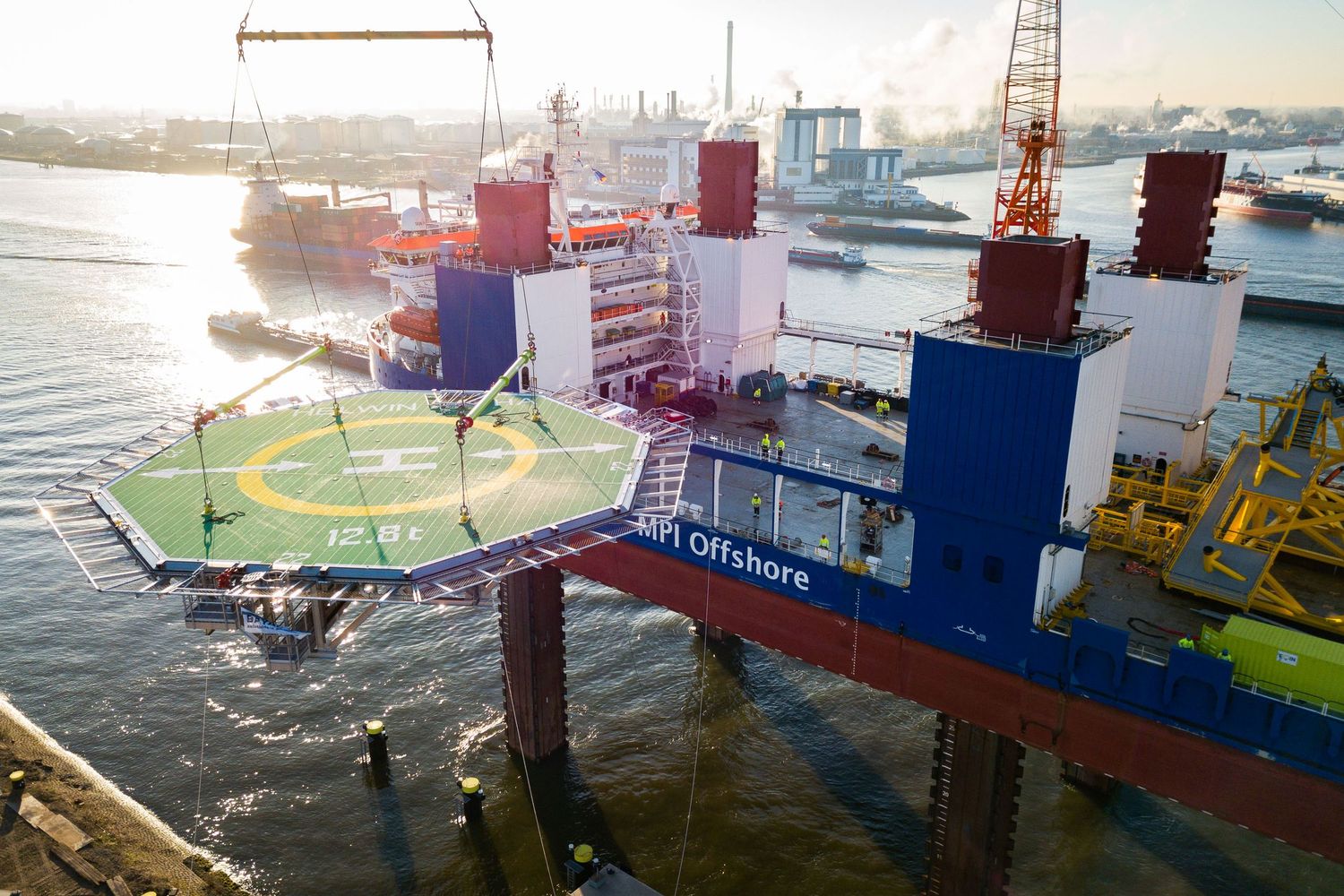 Cargo vessels and cranes at busy port terminal during sunset operations.
