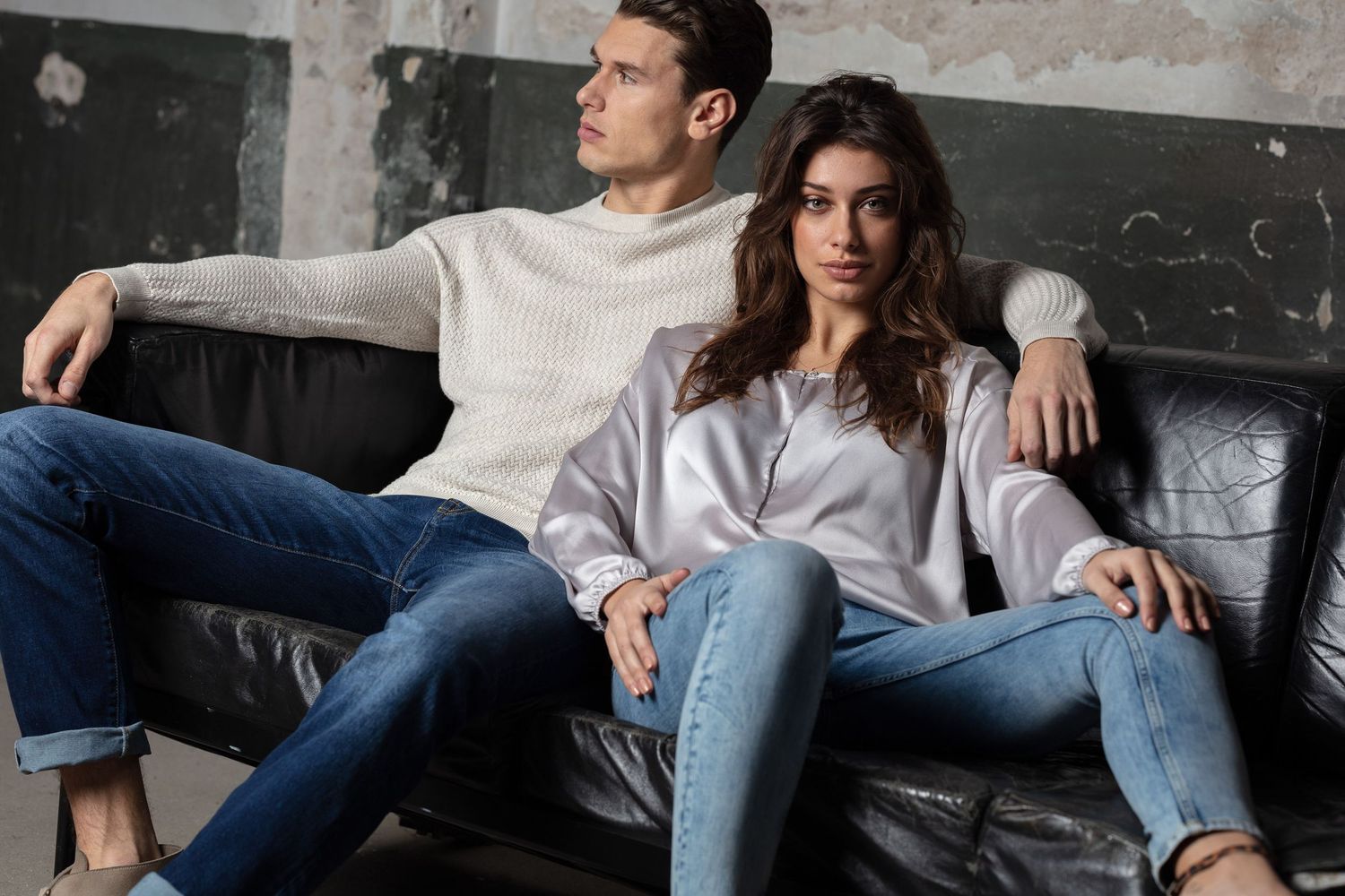 Casual lifestyle scene on grey couch against industrial concrete wall background.
