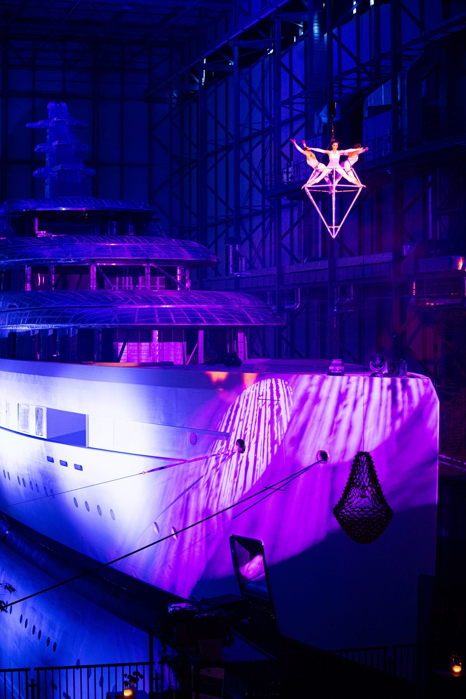 Purple and blue LED lights illuminate a winter snow tubing hill with neon geometric shapes glowing in the night sky.