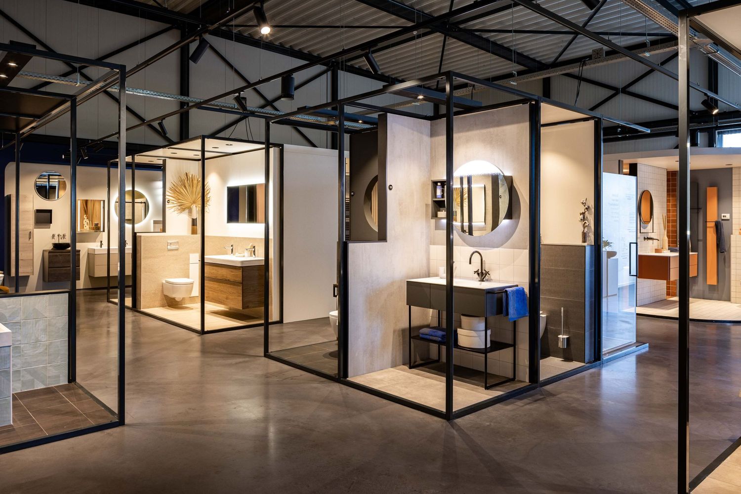 Modern art gallery interior with black metal framed glass walls and polished concrete floors showing multiple exhibition spaces.