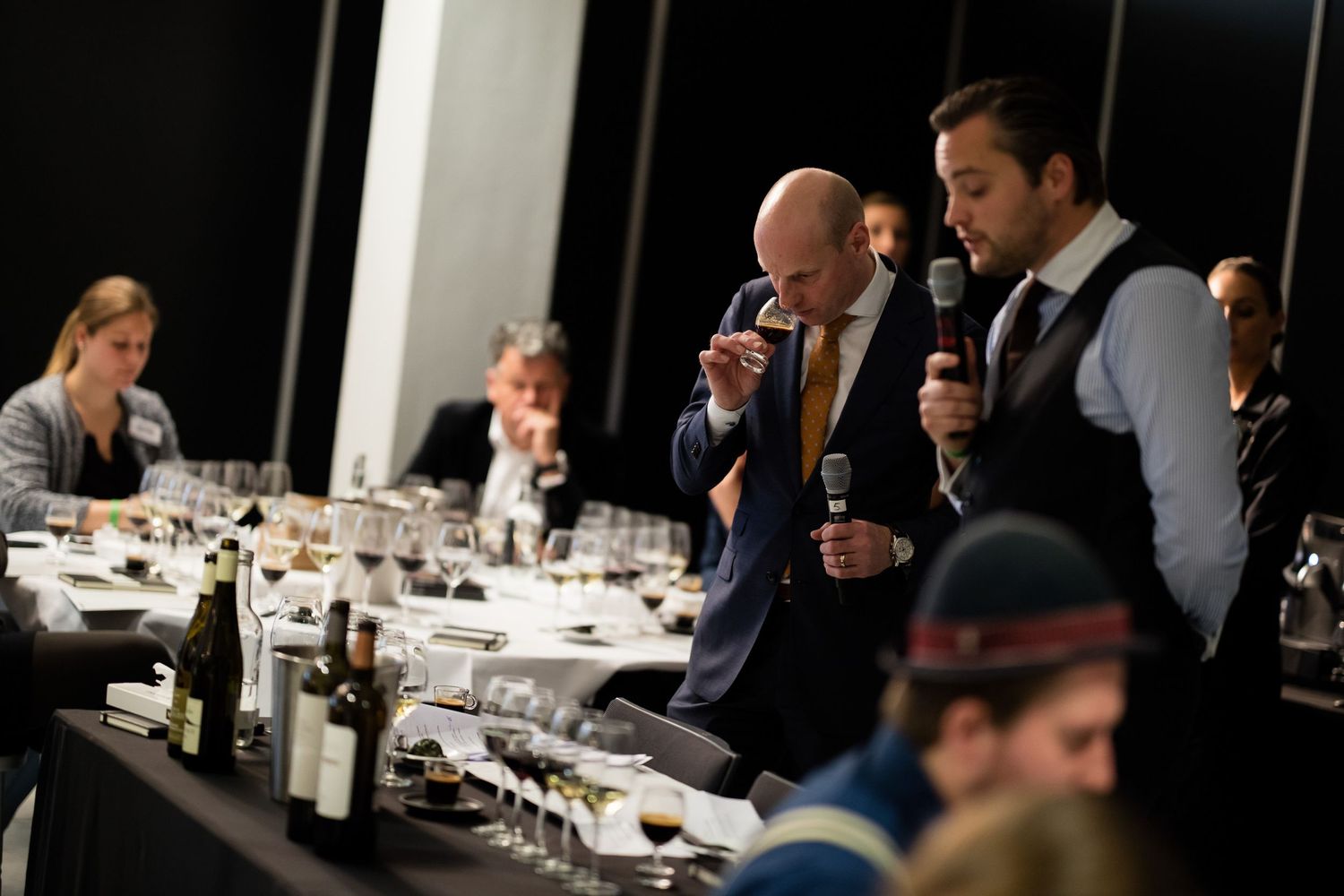 Wide shot of wine tasting event with multiple participants at tables.