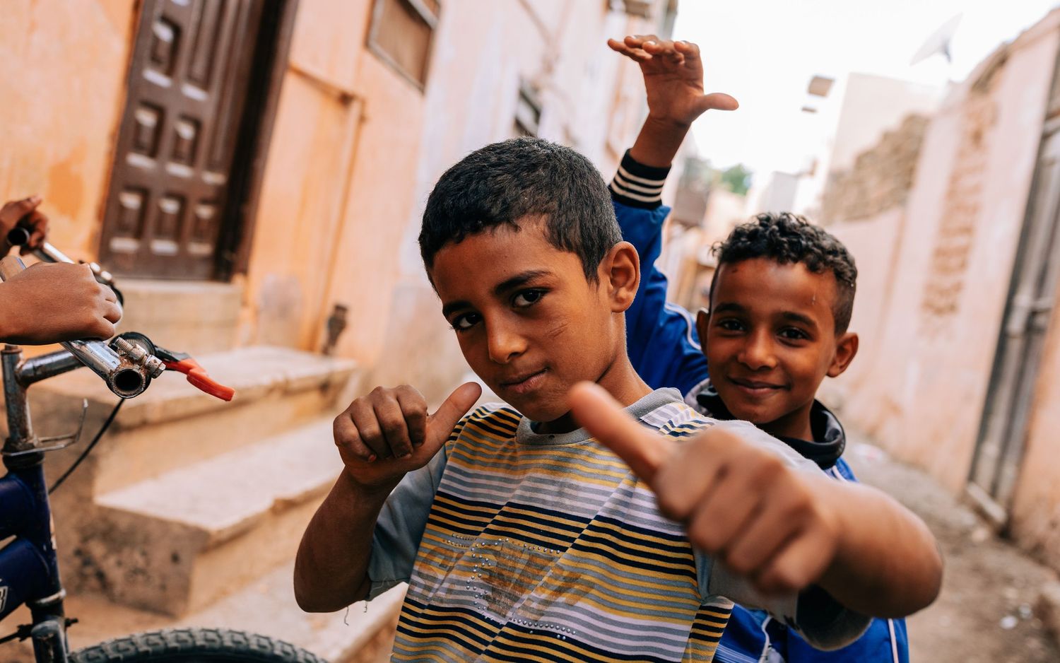 Children playing in a narrow alleyway with peach-colored walls.