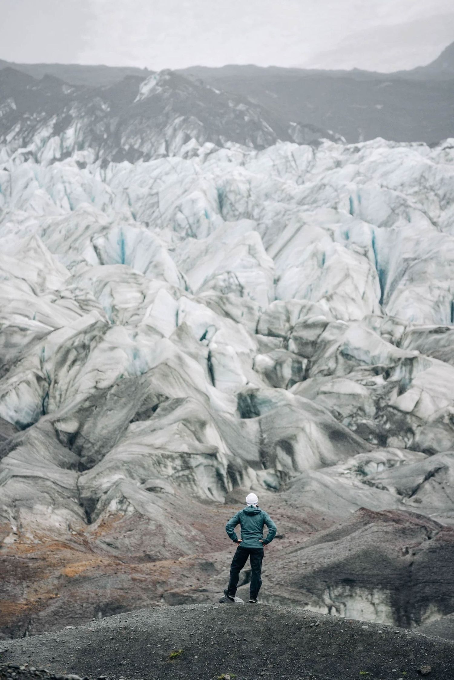 A lone adventurer stands before a vast glacier landscape with jagged ice formations in the background.