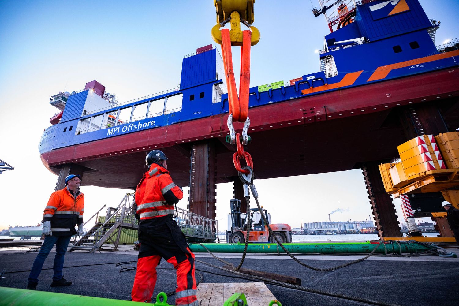 Maritime workers operating equipment on deck of industrial vessel.