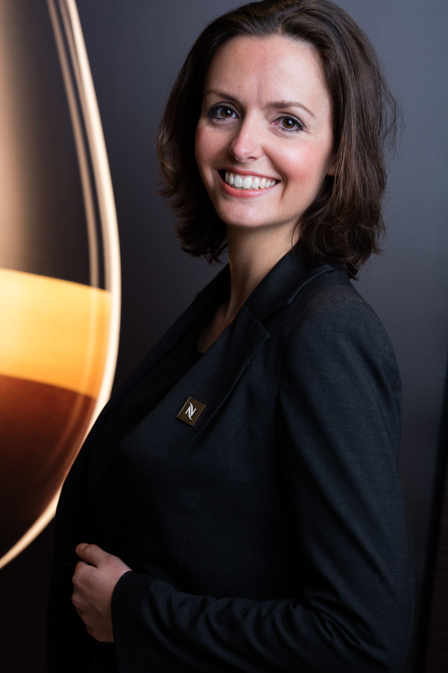 Portrait against dark background with wine glass silhouette.