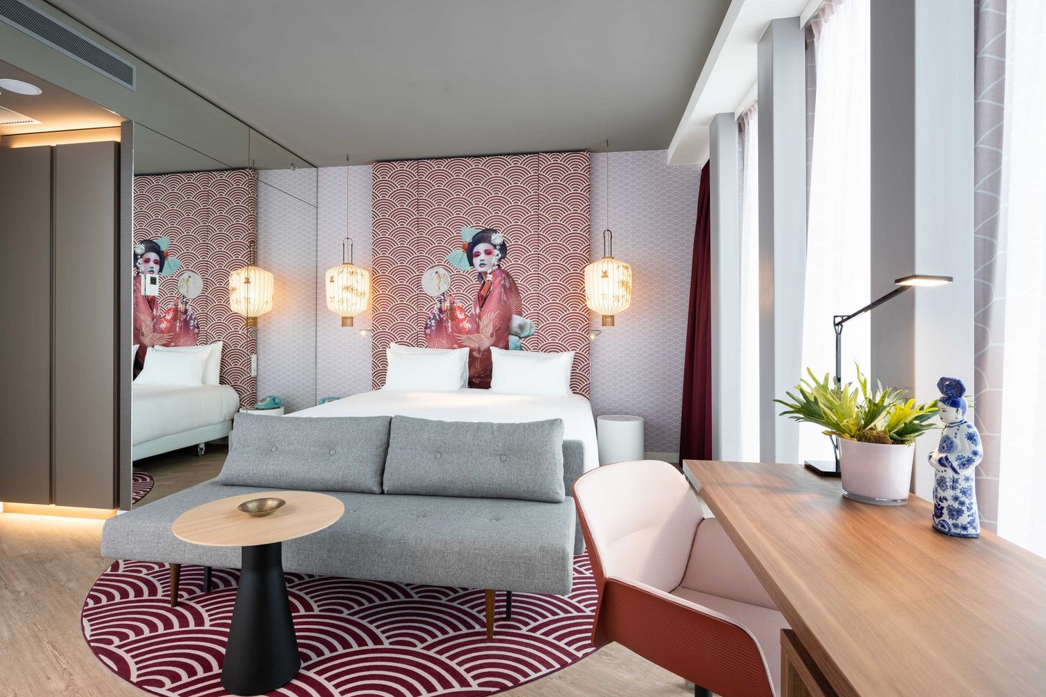 Modern hotel room interior with pink accents features geometric patterns and sleek furnishings in natural light.