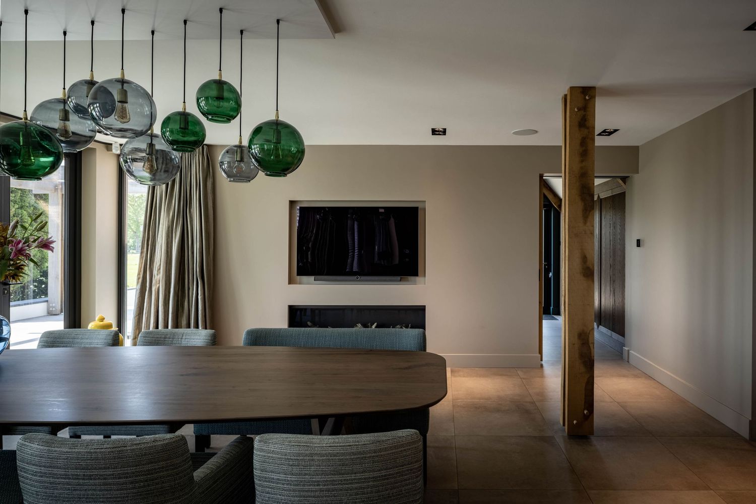 Modern open concept living space with dark wood floors, white walls, and green glass pendant lights.