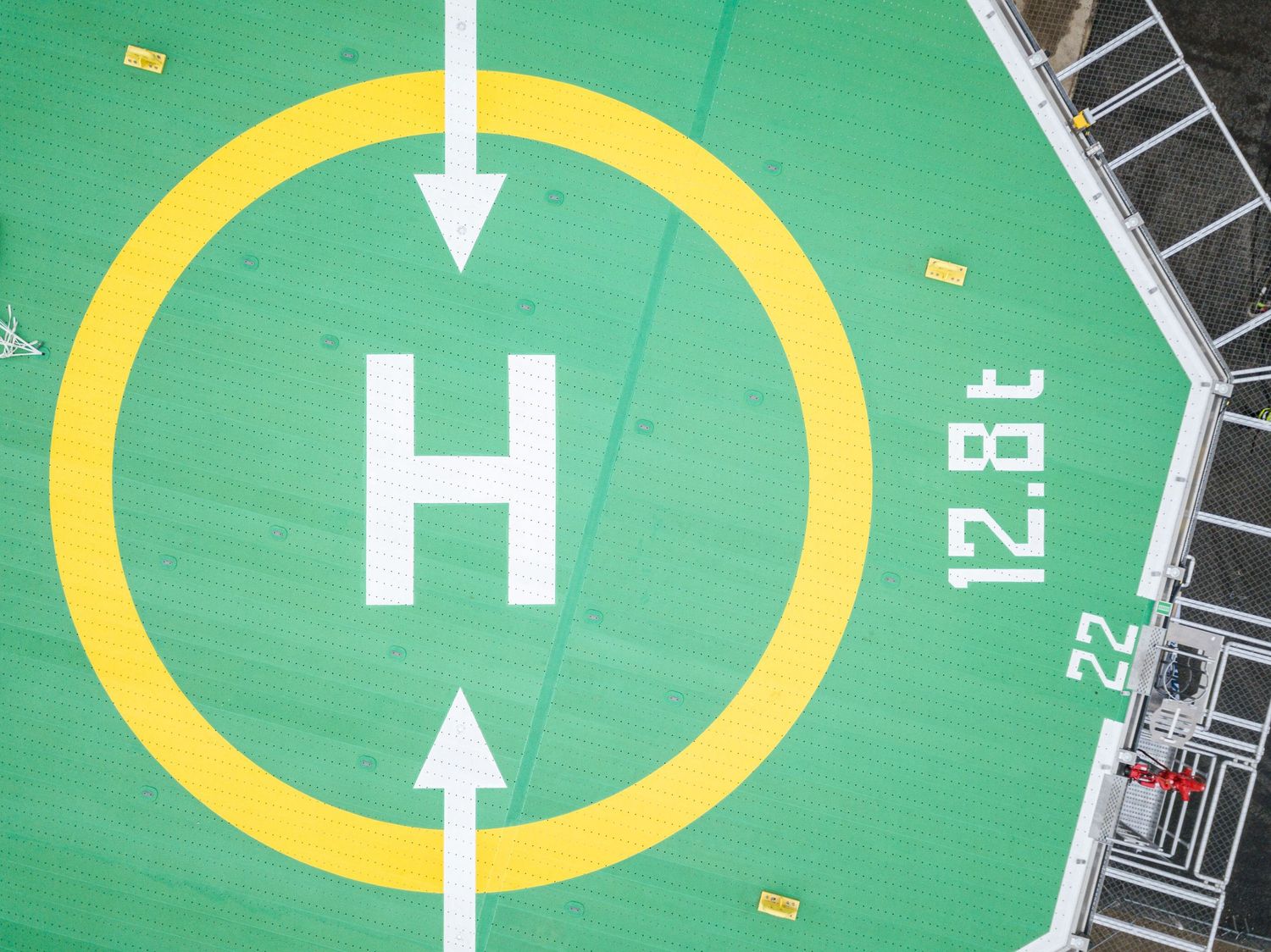 Green helipad markings on offshore platform deck with directional arrows.