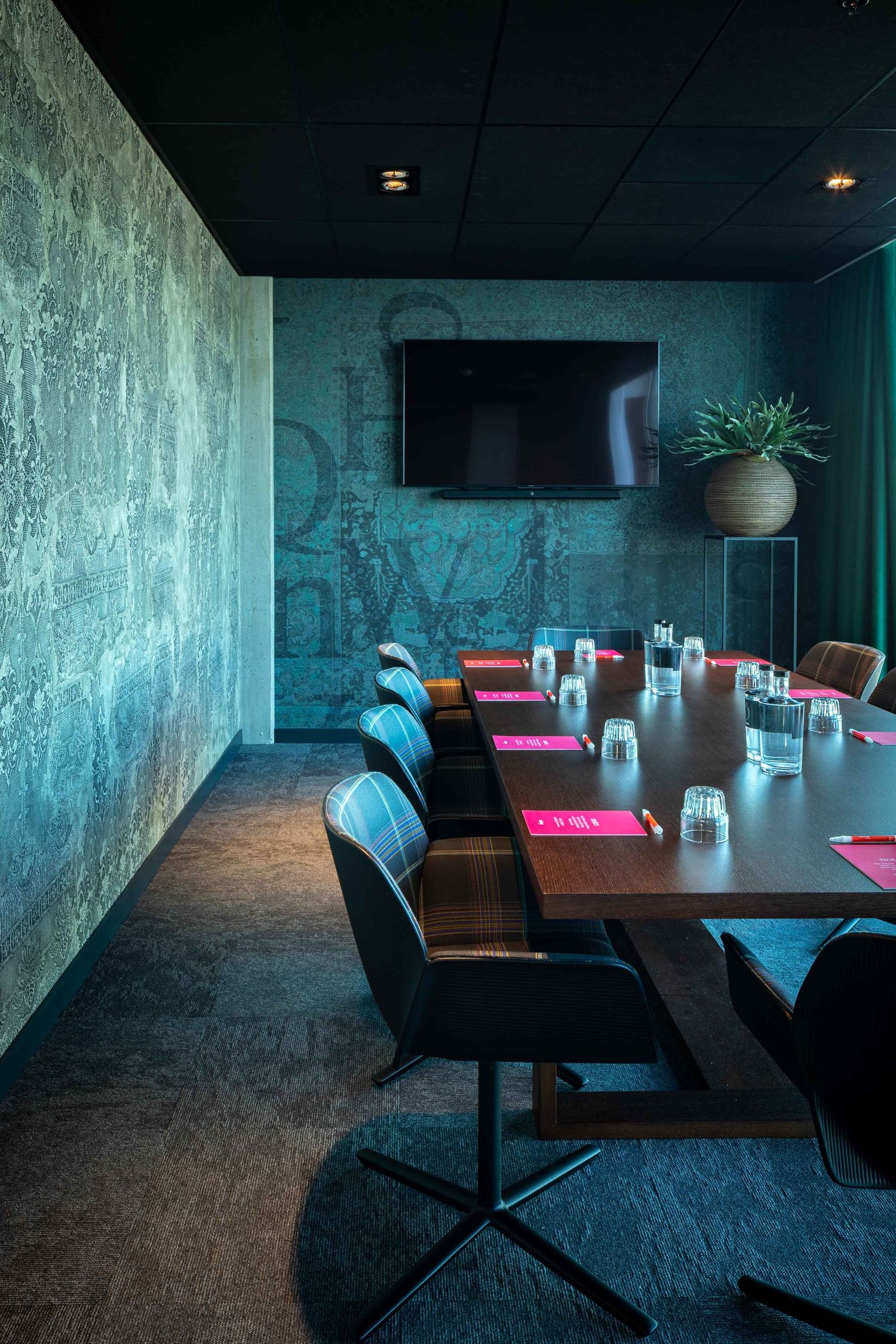 Modern restaurant interior with dark teal walls and minimalist furniture creates a moody, atmospheric dining space.