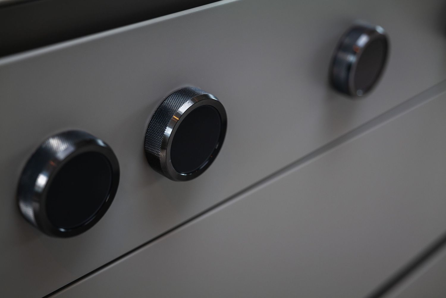 Close-up view of three black control knobs on a gray appliance panel.