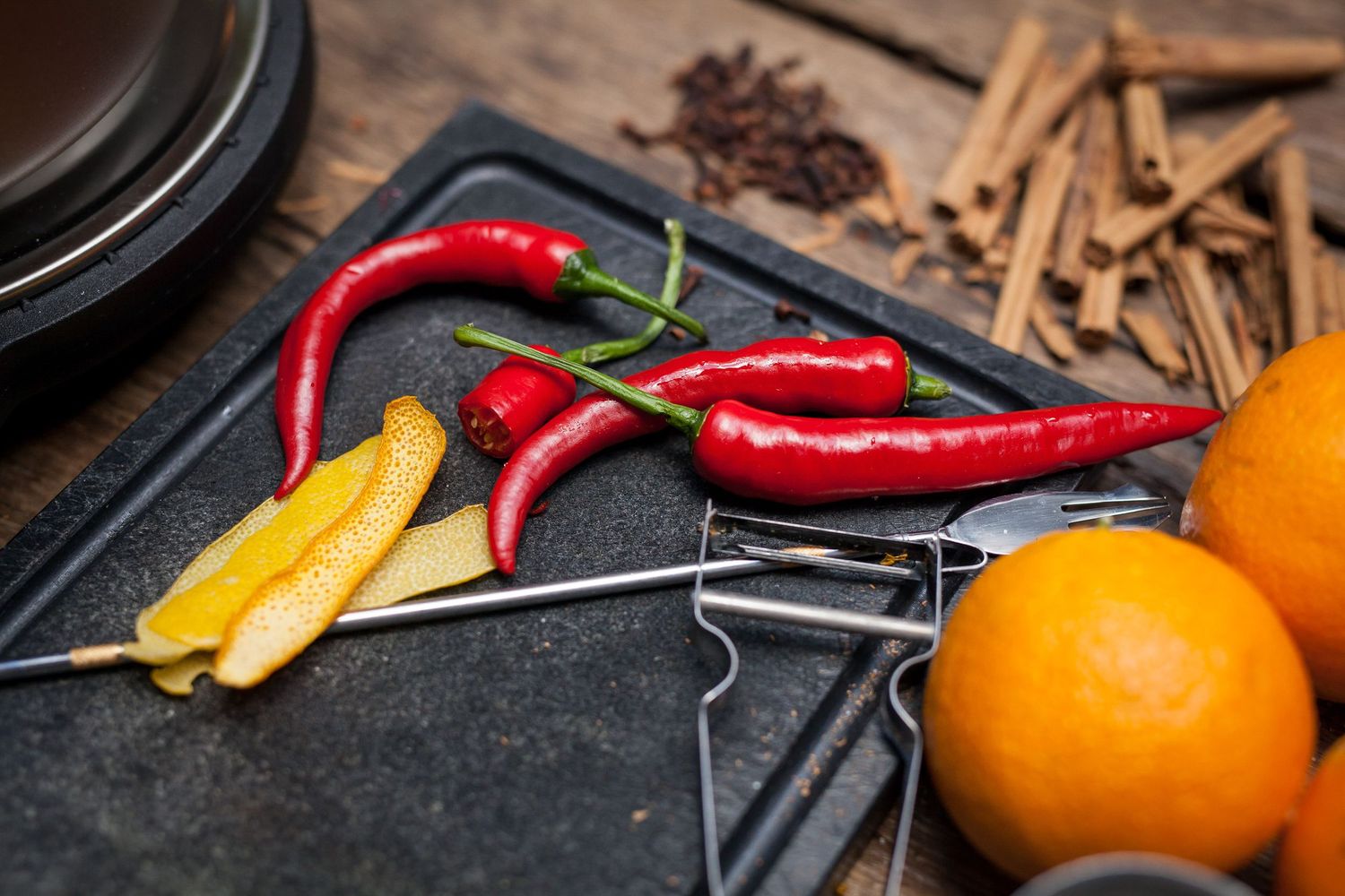 Fresh ingredients including red chili peppers, citrus, and spices arranged on dark surface.