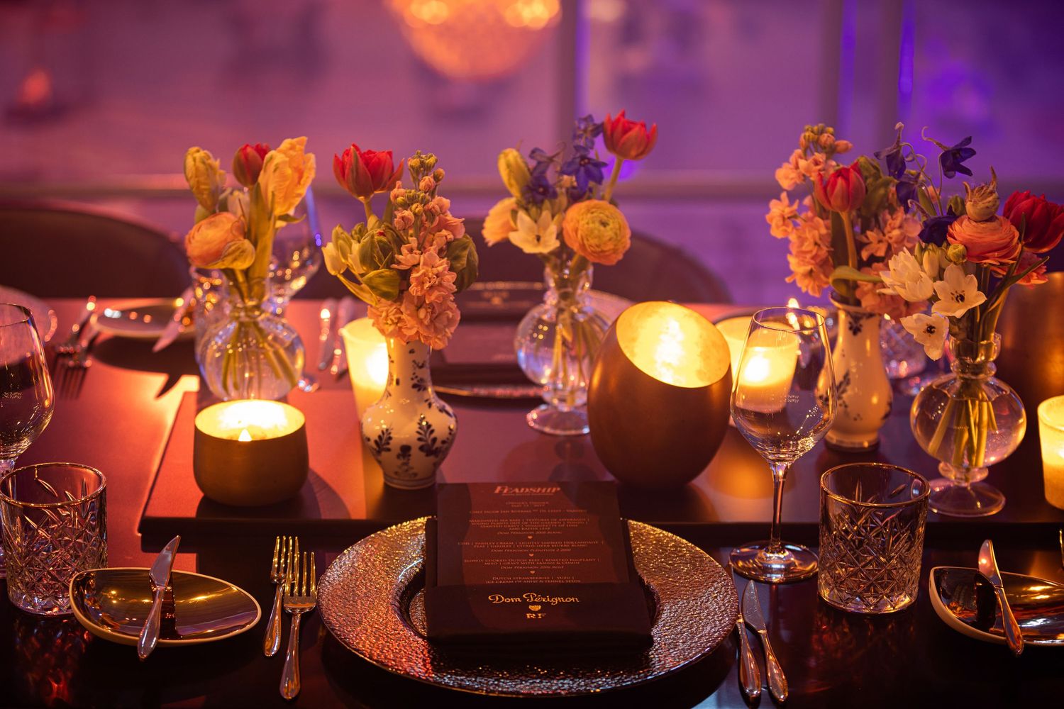 Elegant table setting with glowing candles and orange floral centerpieces creating romantic evening ambiance.