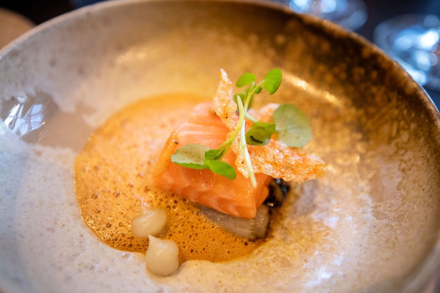 Close-up of fresh salmon fillet being prepared with herbs and seasonings on a rustic wooden surface.