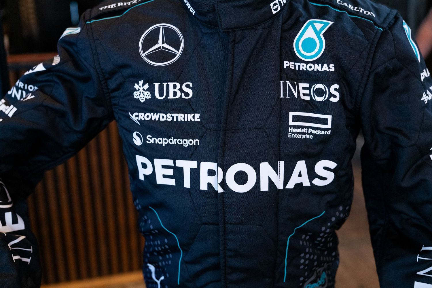 Close-up detail of a Mercedes Petronas Formula 1 racing suit with team sponsors and logos.