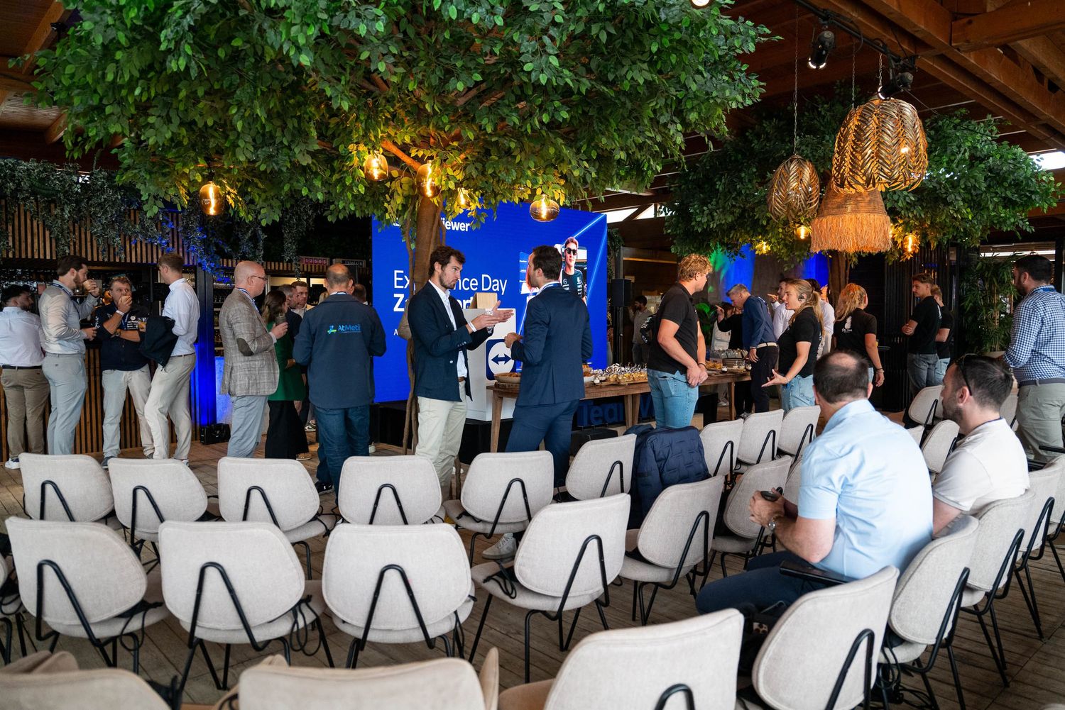 Corporate event venue with rows of chairs and attendees under decorative tree lighting.
