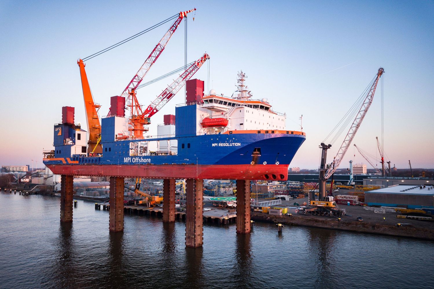 Industrial shipping cranes line the waterfront at a busy commercial port.