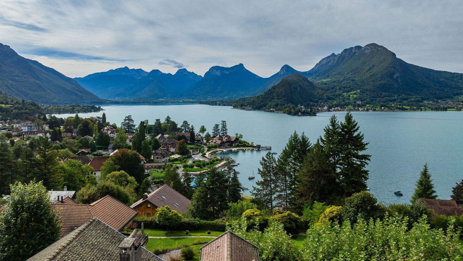 Sweeping panorama of a mountain lake surrounded by alpine peaks and waterfront homes.