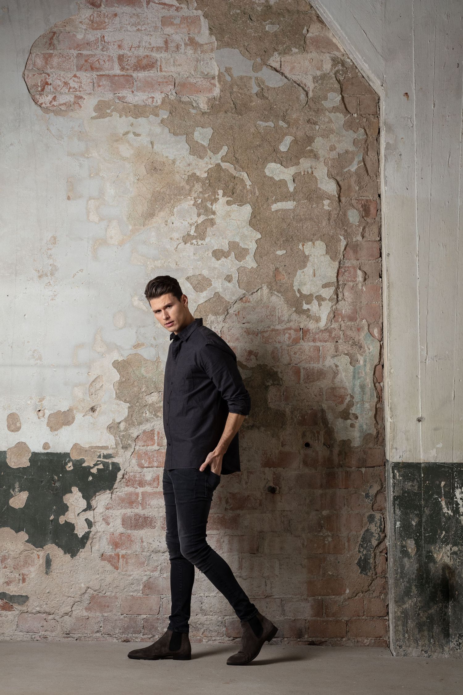 Modern minimalist fashion against weathered brick and concrete wall.