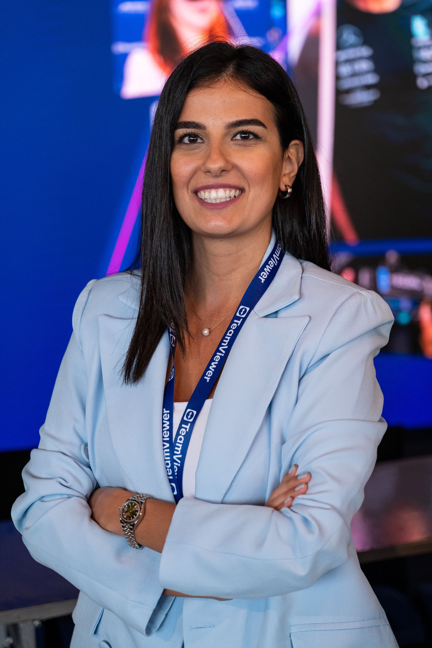 Professional in light blue blazer at corporate event with TeamViewer branding.
