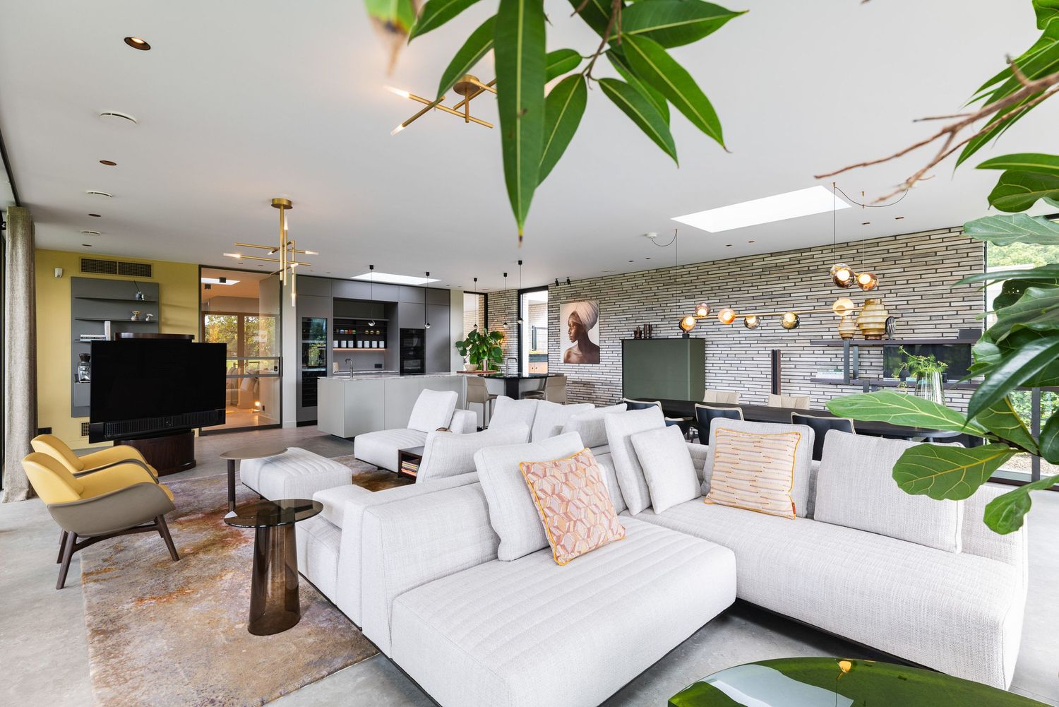 Modern living room features white sectional sofa, hanging plants, and natural light streaming through large windows.