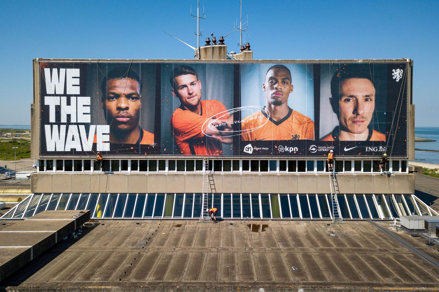 Aerial view of We The Wave Netherlands football team banner on stadium exterior wall.