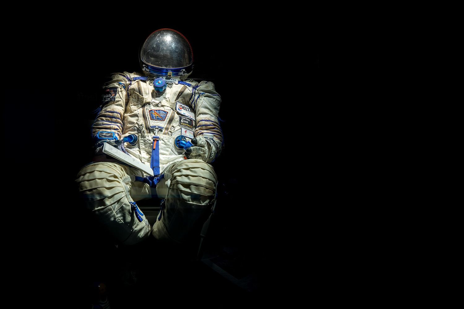 A vintage Soviet space suit displayed against a dark background, illuminated to highlight its blue and gray design.