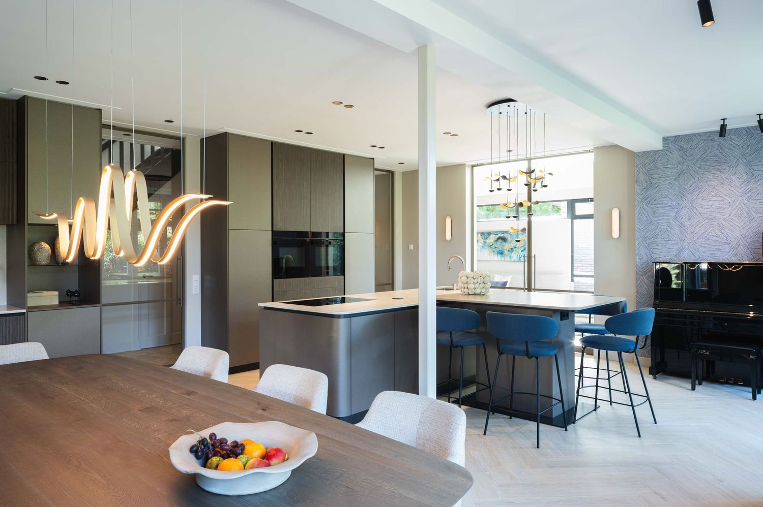 Modern open concept living room and kitchen with sleek white cabinets and pendant lighting over a breakfast bar.