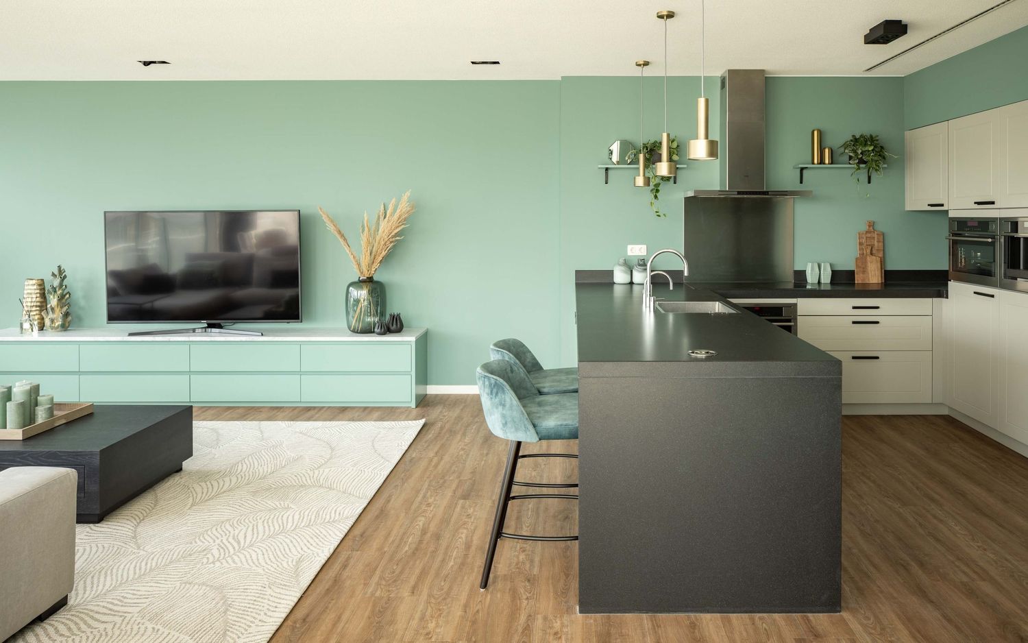 Modern kitchen interior with black island, white cabinets, wood flooring and mint green accent wall.