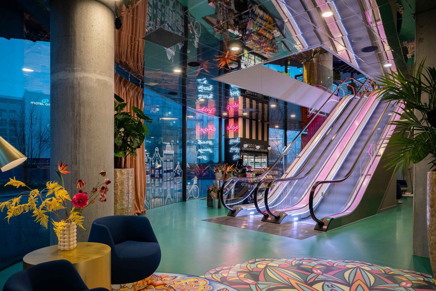 Modern shopping mall interior with curved glass ceiling, escalators, and colorful lighting design creating a futuristic atmosphere.